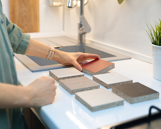 A woman choosing kitchen countertop material texture from samples.