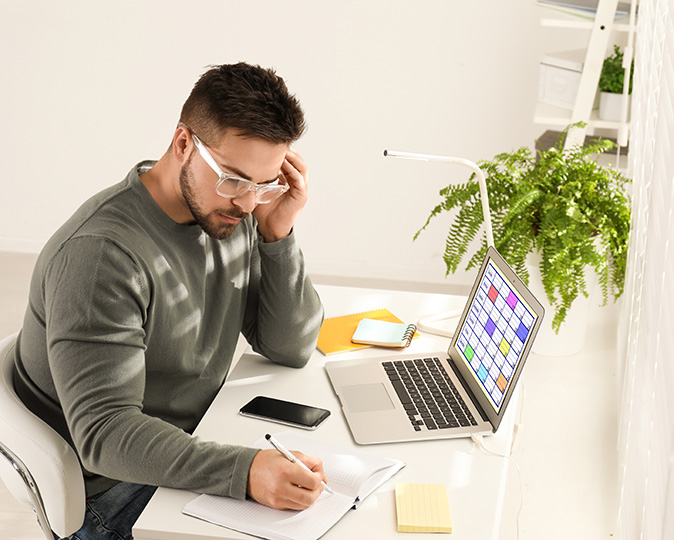 A young man checks a calendar app for his maintenance schedule on his laptop.