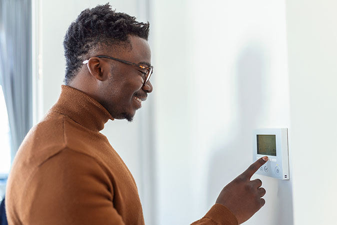 A man adjusts a thermostat.