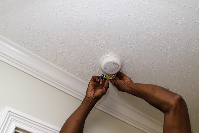 A man changing the battery in a smoke detector.