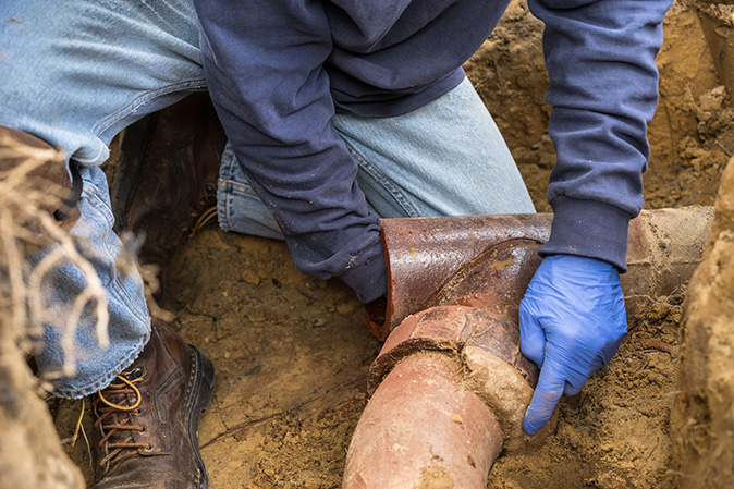 A man digging out a clogged sewer line to fix it.
