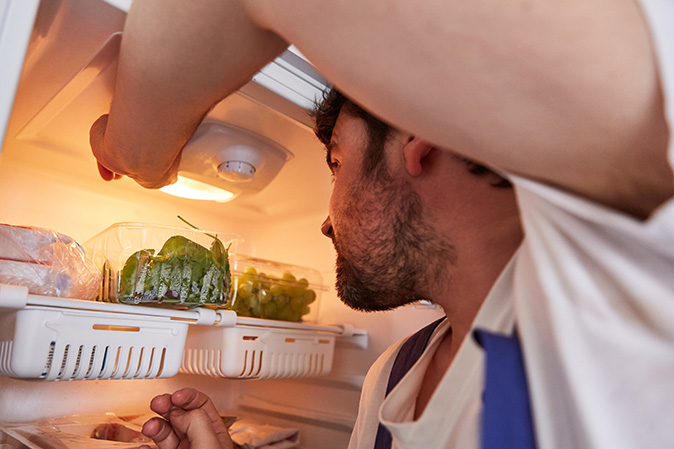 A homeowner is inspecting the light in a refrigerator.