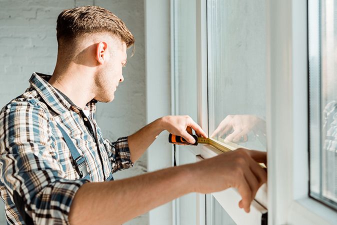 A handyman measuring the width of a window.