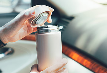Woman’s hand holding an insulated travel mug