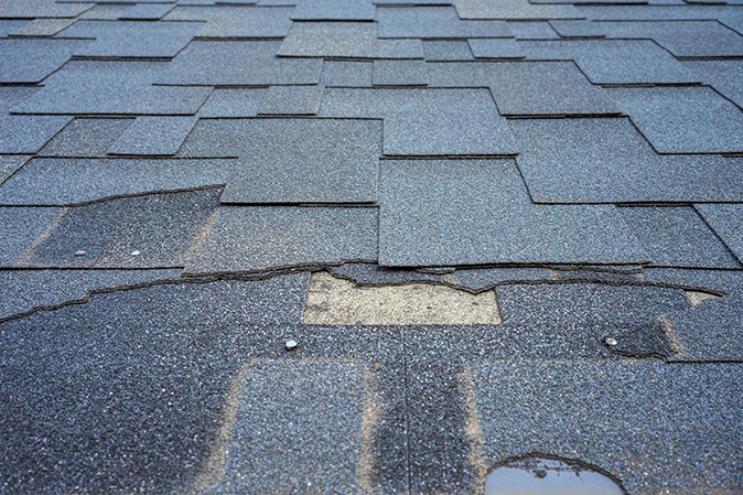 Close up of damaged roof shingles in need of repair.
