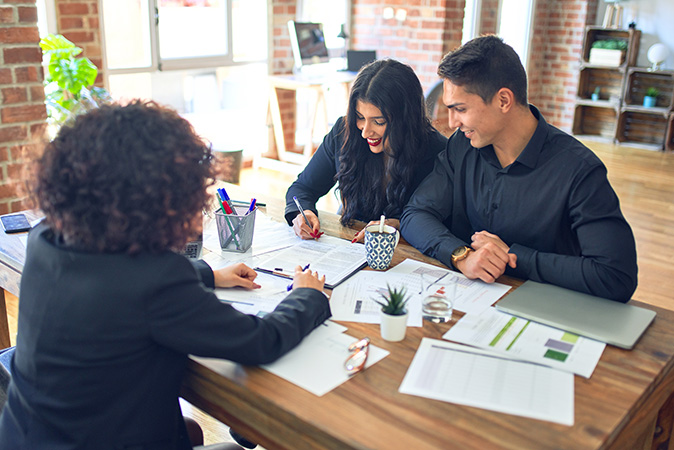 A young couple sits down with their real estate agent to review mortgage terms.