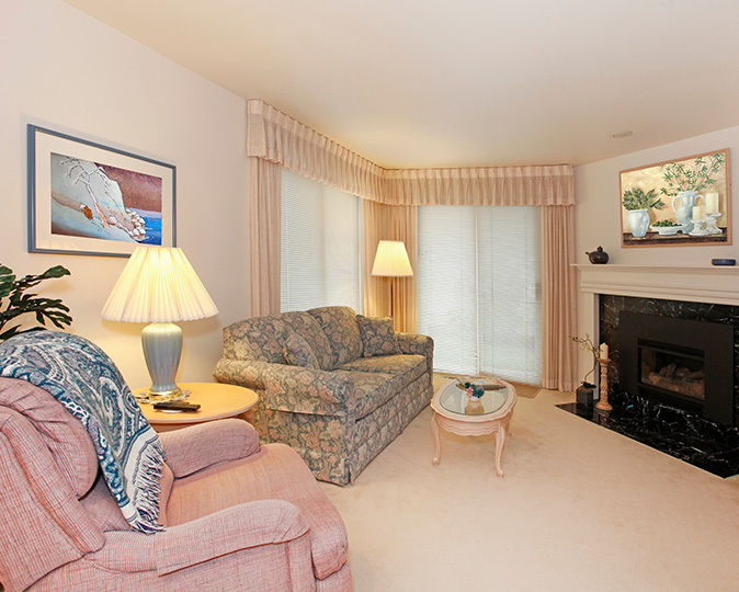 An outdated living room with beige carpet and floral furniture.