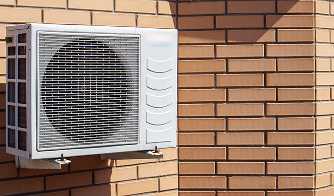 Outdoor mini-split component mounted on a brick wall