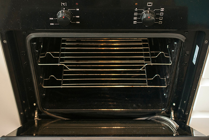 A torn oven door seal that needs replacing leans against the open door.