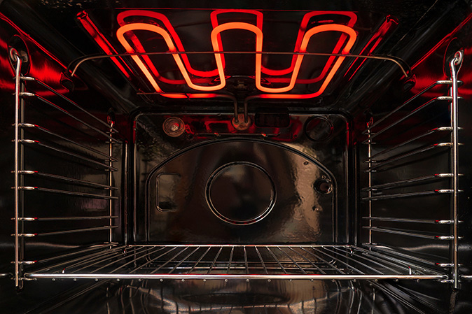An inside view of an oven with a hot heating element.
