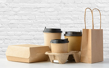 Several cardboard and paper food storage items in front of a whitewashed brick wall