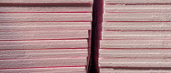 A stack of pink rigid insulation foam made from polystyrene and used to insulate homes.