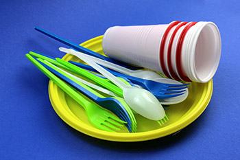 A stack of single-use plasticware including cups, plates, and utensils