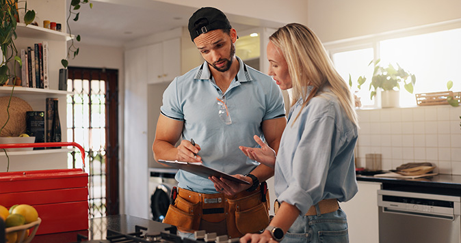A homeowner talks with a plumber holding a clipboard about scheduling another visit.