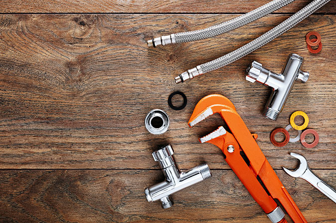 Set of plumbing tools, washers, and hoses on wooden table