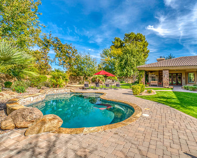 Backyard pool and spa surrounded by a stone patio.