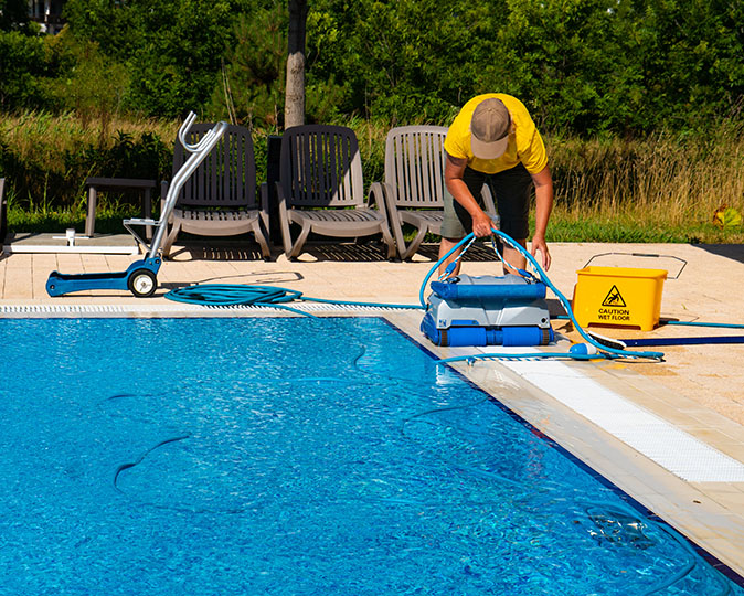 A pool technician gets equipment ready to use for cleaning a home swimming pool.