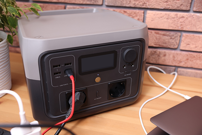 Image shows a portable power station being used to charge a laptop.