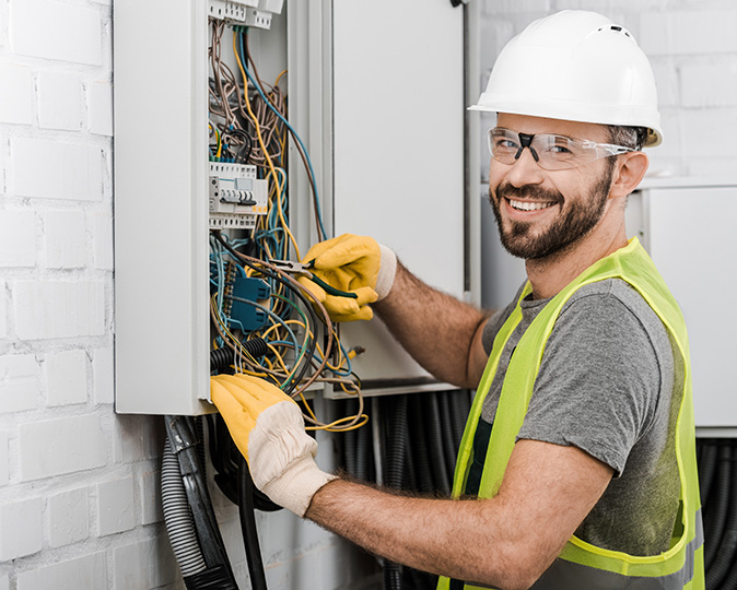 A professional electrician works on a home fuse box.