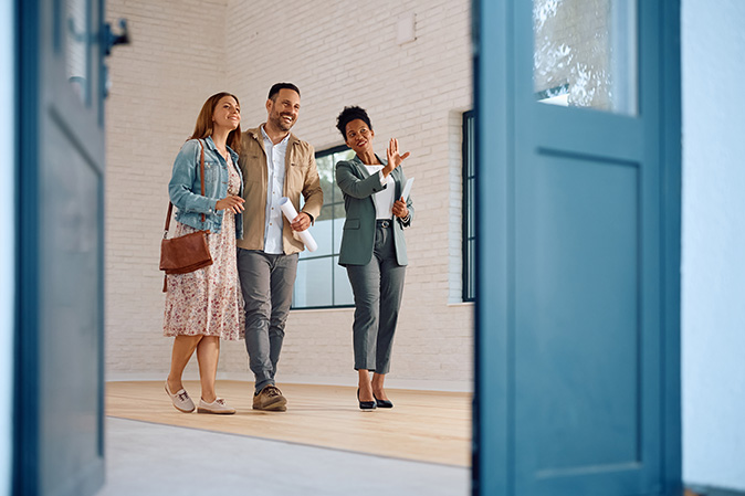 A young couple is on a private home tour with their real estate agent.