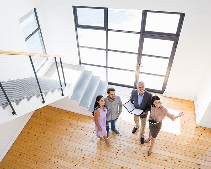 Real estate professionals show a brightly lit home to potential buyers.