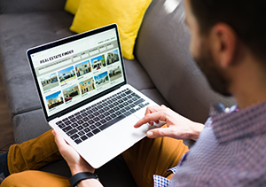 Home buyer using laptop to review homes for sale