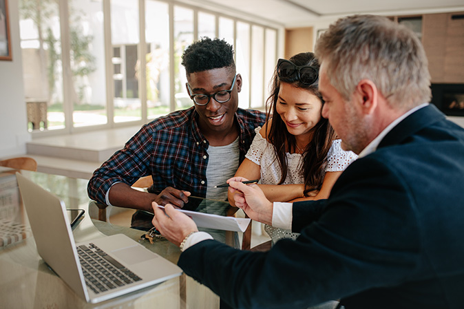 A real estate agent presents new homeowners with their home warranty plan.