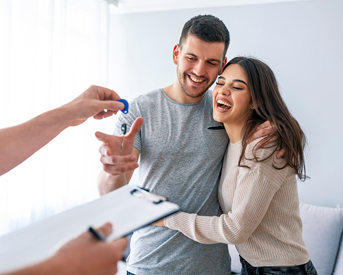 A young couple laughs as they get the keys to their new home.