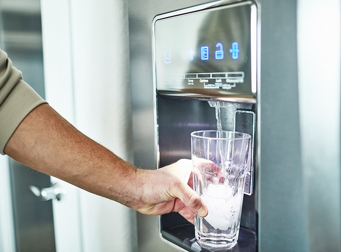 Person getting water from a fridge dispenser.