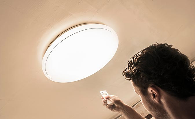 A person installing a dimmer switch to a wall in their home.