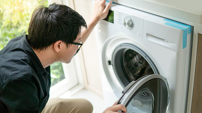 A young man checking the interior of the dryer.