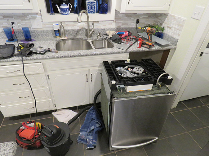 A dishwasher out on the floor being repaired.