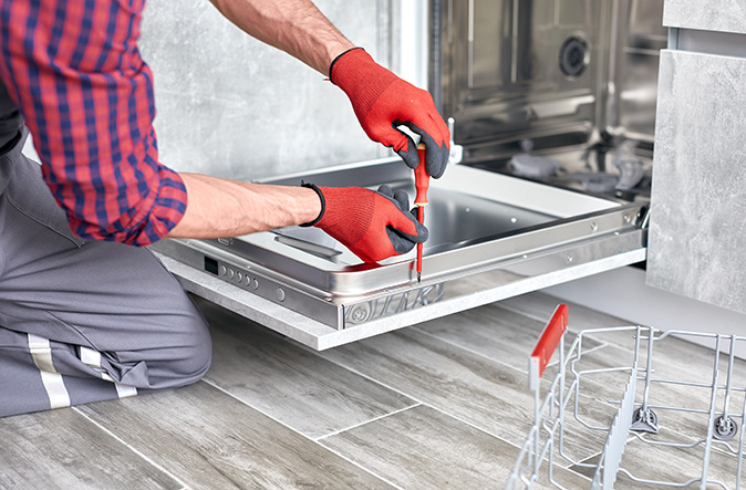 A man repairing the door of a dishwasher.