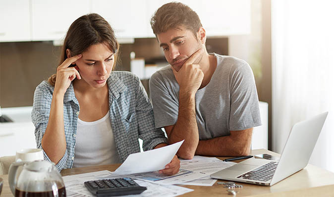 A couple in their kitchen goes over financial documents together over coffee.