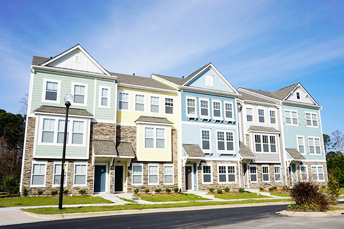 A row of multicolored townhomes set against a bright blue sky.