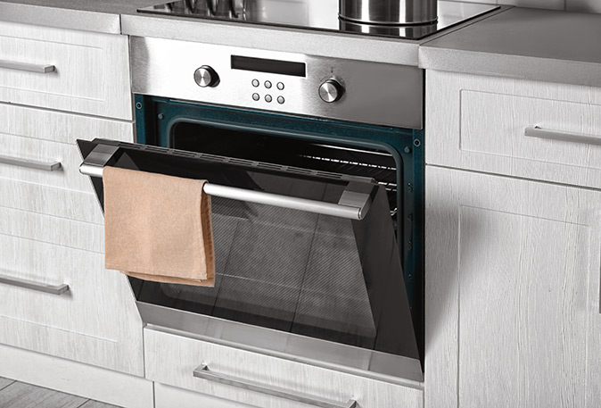 The oven door is ajar on a self-cleaning electric oven in a kitchen.