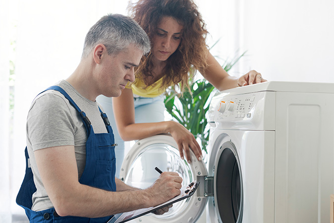 A technician looking for issue with a homeowner's broken washing machine.