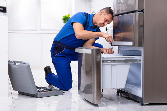 A serviceman making repairs on a freezer.