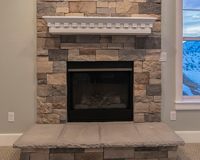 Floor to ceiling stone fireplace with wintry scene out the window to the right.