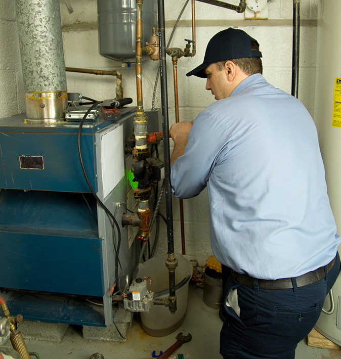 Furnace repair technician fixes furnace located in the basement.