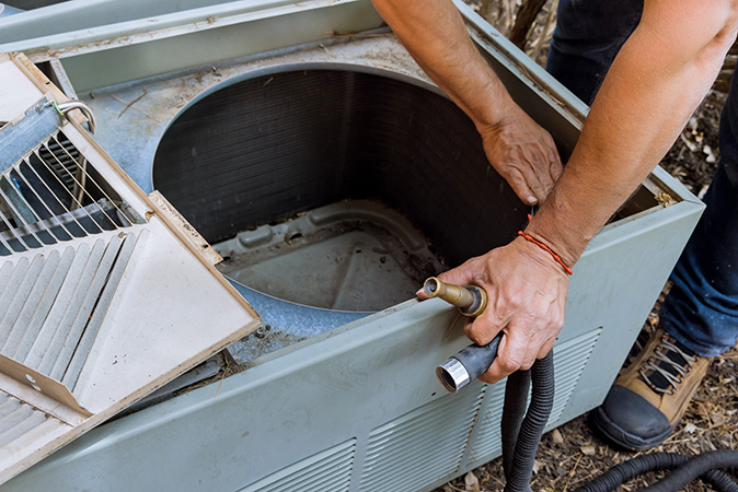 A professional technician does deep maintenance work on a homeowner’s air conditioner.