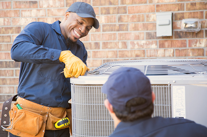 Two people smile while working on an HVAC replacement project.