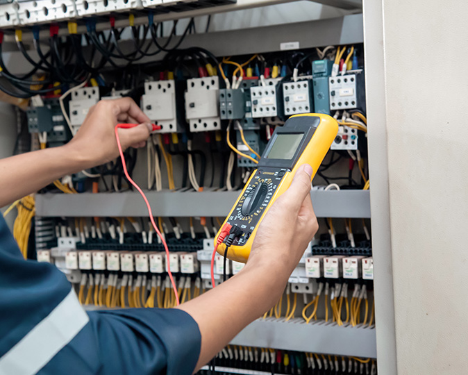 An electrician tests a circuit breaker using a multimeter device.