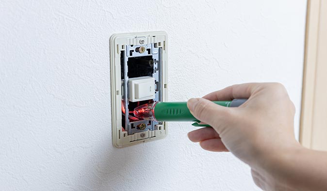 A man testing a dimmer lightbulb remotely after installing a new dimmer switch.