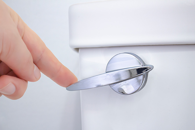 A person pressing the toilet handle down to test flushing