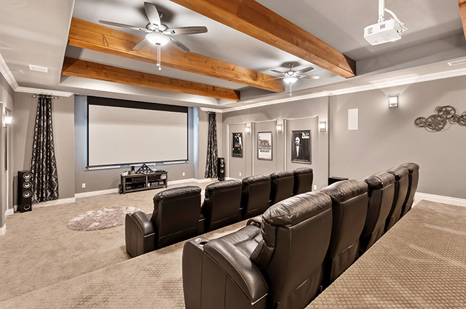 A home movie theater with a projection screen and dark brown leather recliners.