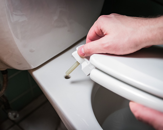 A person installs a new toilet seat.