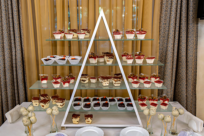 A multi-tiered glass dessert stand is filled with all kinds of scrumptious holiday desserts.