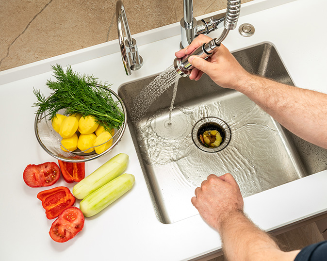 A homeowner washes food waste into a dispenser.