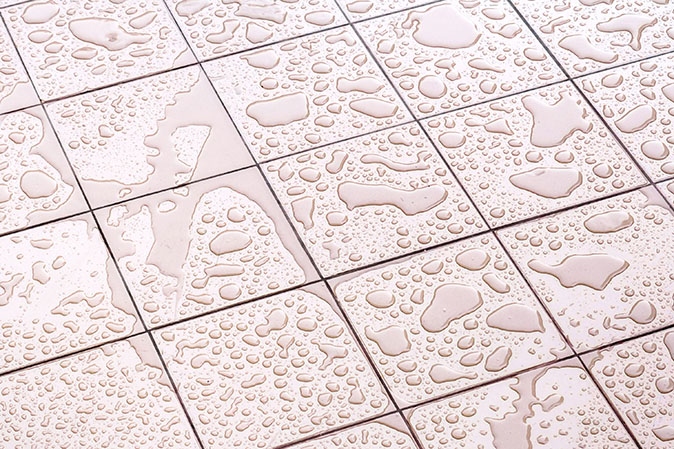 A small layer of water sits on a bathroom tile floor.